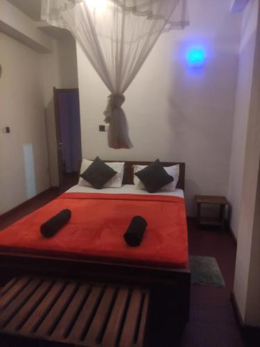 Un dormitorio con una gran cama roja con almohadas negras en Nice Ella, en Ella