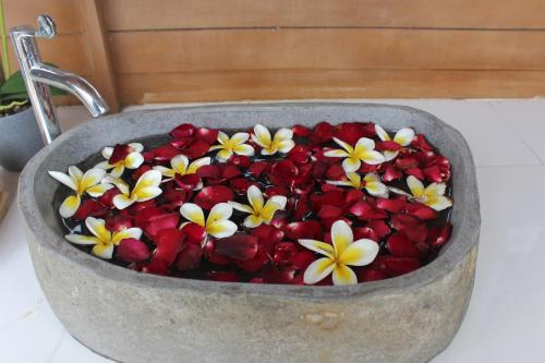 a stone bowl filled with red and white flowers at Green Village Jungle Resort in Nusa Penida