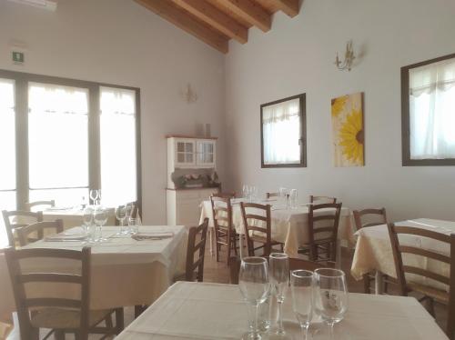 un comedor con mesas y sillas y copas de vino en Agriturismo Honey Farm, en Piazzola sul Brenta