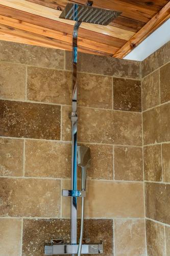 a shower in a bathroom with a stone wall at Bungalow L'escale de Takamaka in Saint-Benoît