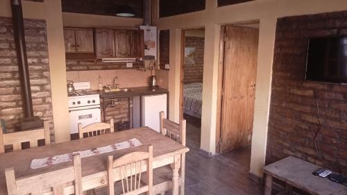 a kitchen with a wooden table and chairs and a kitchen with a stove at Cabañas de los Andes in Uspallata