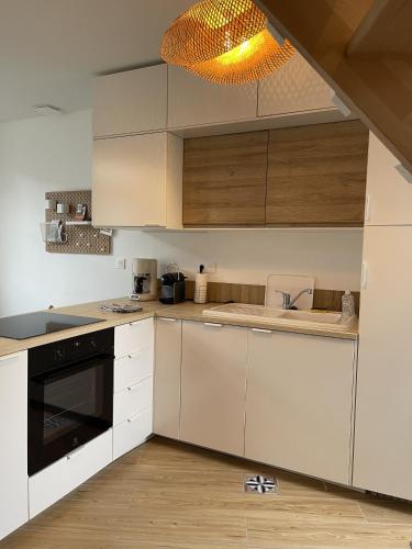 une cuisine avec des armoires blanches et un évier dans l'établissement Maison Les 3 oies, au Crotoy