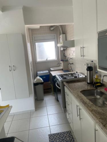 a kitchen with a sink and a stove and a window at Apartamento na Praia das Asturias - Pé na Areia in Guarujá