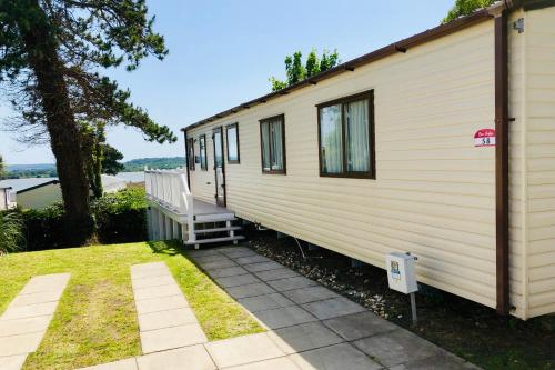 una casita blanca pequeña con porche y escalera en Family Seaside Retreat Private Stay at 5-Star Rockley Holiday Park Poole, en Poole