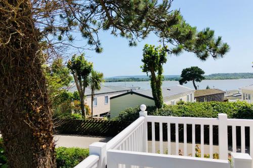 a white porch with a white fence and a tree at Family Seaside Retreat Private Stay at 5-Star Rockley Holiday Park Poole in Poole