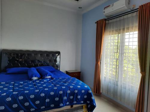 a bedroom with a blue bed and a window at Villa Bukit Nirwana in Bogor