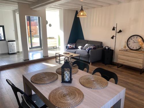 een woonkamer met een tafel en stoelen en een bank bij Jolie petite maison solognote in Pierrefitte-sur-Sauldre