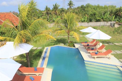 an overhead view of a swimming pool with chairs and umbrellas at Green Village Jungle Resort in Nusa Penida