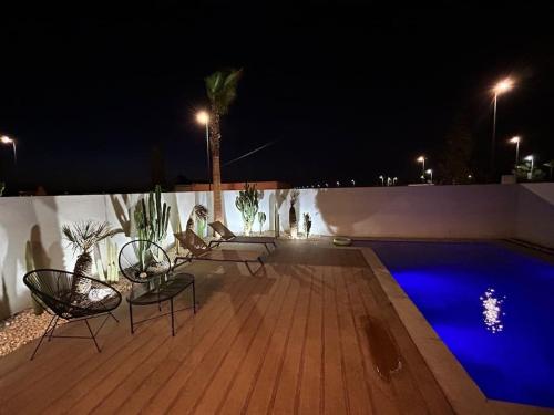 a deck with chairs and a swimming pool at night at Villa California vue Atlas avec piscine chauffée in Marrakesh