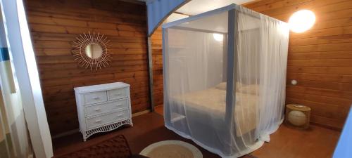 a bedroom with a bed and a dresser and a mirror at HOME CONTAINER RESORT Terre in Sainte-Rose