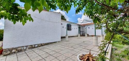 een wit gebouw met een bakstenen binnenplaats ervoor bij Casa rural en naturaleza con BBQ in Villar de Cañas