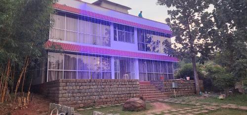 a building with purple lights on the side of it at Glass House - The Farm in Yelagiri