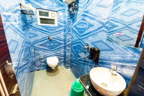 uma casa de banho em azulejos azuis com um WC e um lavatório em Aheri Residency em Digha
