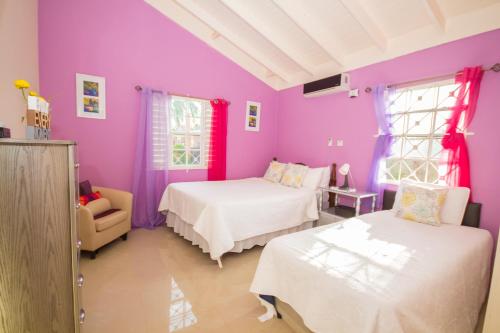 Habitación púrpura con 2 camas y silla en Ocho Rios Drax Hall 1 Bedroom sleeps 1-3 persons, en Saint Annʼs Bay