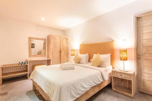 een slaapkamer met een groot wit bed en een spiegel bij Villa Jalak in Seminyak