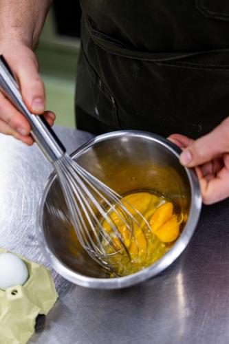a person is stirring a bowl with a whisk at Hotel Ny Hattenæs in Silkeborg