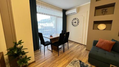 een woonkamer met een tafel en stoelen en een klok bij Gondola Apartments Lux in Bansko
