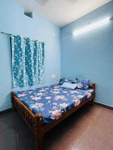 a bedroom with a bed with a blue wall at Sri sai home Stay in Udupi