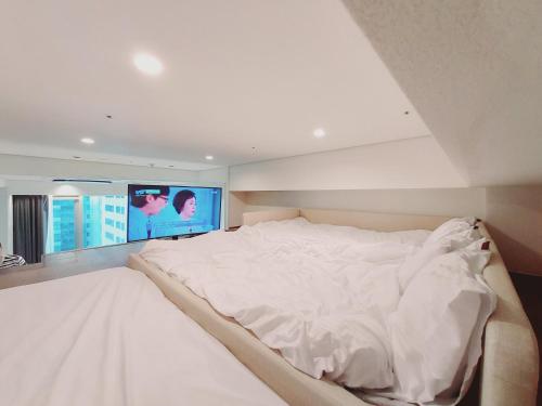 a large white bed in a room with a tv at Coex Stay in Seoul