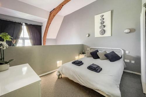 a bedroom with a white bed with blue pillows on it at Lofty Apartment in Plymouth in Plymouth