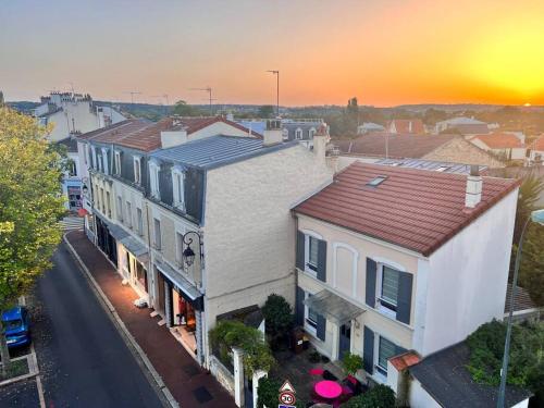 einen Blick über eine Straße mit Häusern und Sonnenuntergang in der Unterkunft Deux pièces, plein centre avec vue sur les toits in Le Vésinet