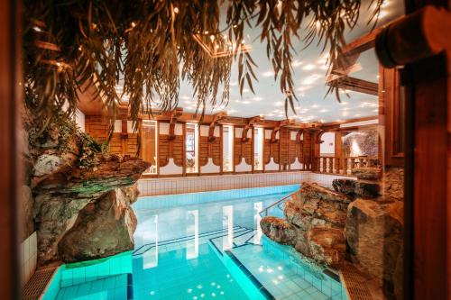 a swimming pool in a hotel with a rock wall at Appartement Hotel Garni Alpenstüble in Mittelberg