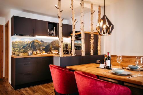 a dining room with a wooden table and red chairs at Hotel Alpenstüble Appartements in Mittelberg