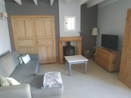 a living room with a couch and a table and a tv at la grange Saint Georges in Hermaville