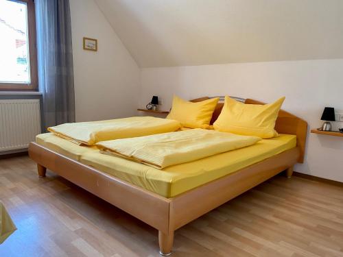 a bed with yellow sheets and pillows in a room at Ferienwohnung Keller in Hagnau