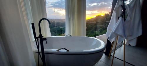 a bathroom with a bath tub in front of a window at Terra de Kurí in Espirito Santo Do Pinhal