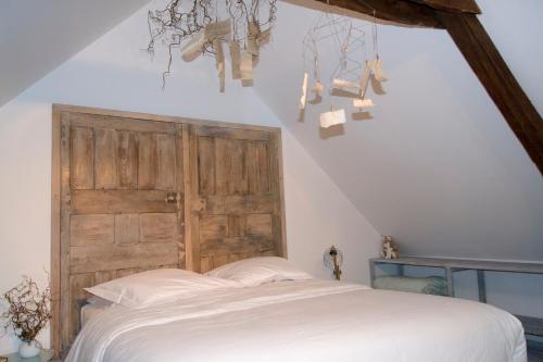 a bedroom with a white bed and a wooden door at Les Hirondelles in Baguer-Pican