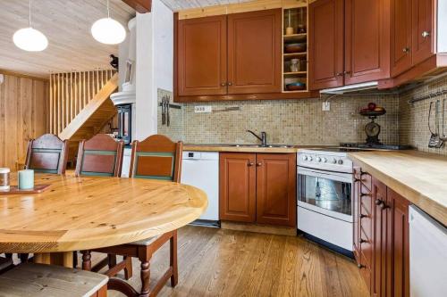 a kitchen with wooden cabinets and a wooden table at Koslig hytte ved Grimsdalen in Dovre