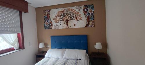 a bedroom with a tree painting above a bed at Apartamento Alentía in Cedeira