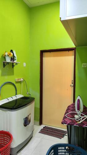 a green room with a bath tub and a door at Yamad Homestay Langkawi in Kuah