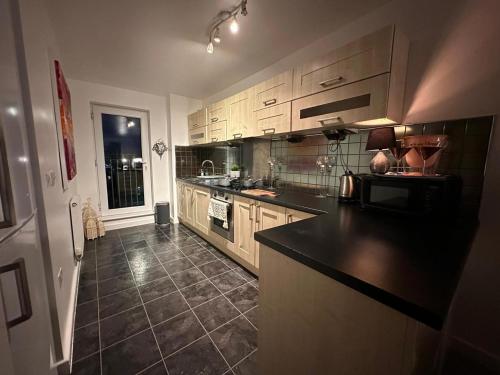 a kitchen with wooden cabinets and a black counter top at Manchester City football Stadium View in Manchester