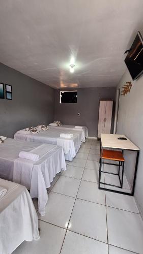 Zimmer mit 3 Betten und einem Tisch in der Unterkunft Canto da Duna Hotel in Barreirinhas