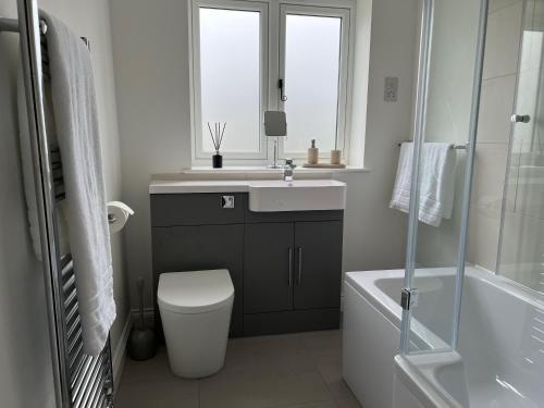 a bathroom with a sink and a toilet and a window at Shepherd's Cottage in Totland