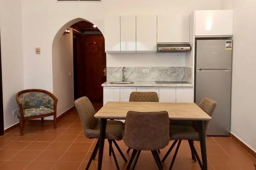 cocina con mesa, sillas y nevera en Appartamento trilocale con vista mare Domina Coral Bay R23121, en Sharm El Sheikh