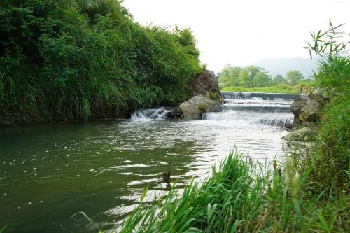 un río con una cascada en el medio en Firfirey Organics- Regenerative Farm Retreat, en Bathāla