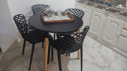 una mesa negra con sillas y una bandeja con vasos. en Casa Isa en Ezeiza