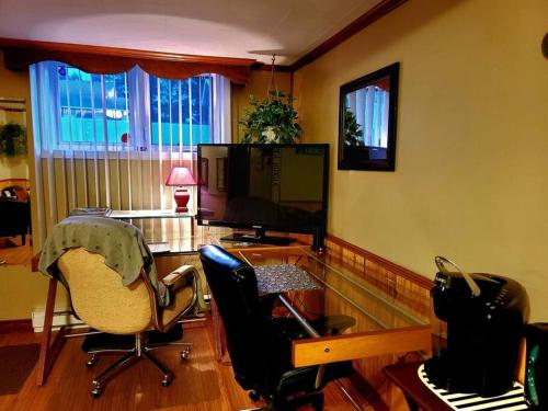 a living room with two chairs and a desk and a television at Gîte du passant SADM, parc de la Gaspésie. in Sainte-Anne-des-Monts