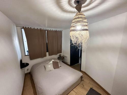 une chambre avec un lit et un lustre dans l'établissement Charmant Mini Loft 57m2 Notre Dame du Mont, à Marseille
