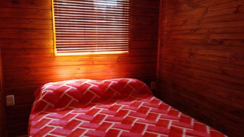 Cama en habitación de madera con ventana en Cabañas azules en Punta del Diablo