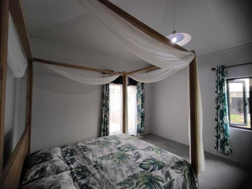 a bedroom with a canopy bed and a window at Naturo Villa 16 in Poste Lafayette