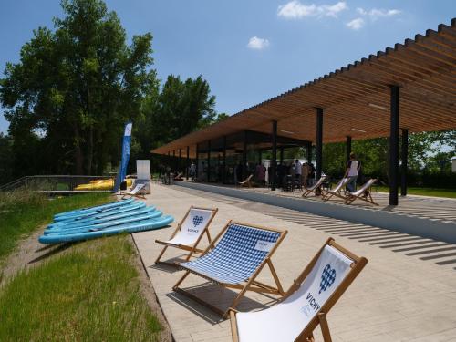 - un ensemble de chaises et de planches de surf sur une terrasse dans l'établissement Tente Lodge pour 5 personnes en bordure de la rivière Allier au sein d'un petit camping, à Saint-Yorre