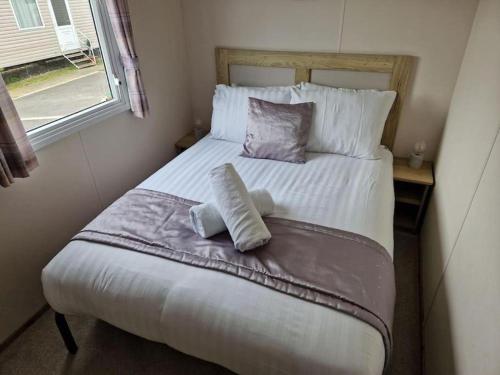 una camera da letto con un letto con due cuscini e una finestra di Weymouth Bay Haven, Preston Road a Weymouth