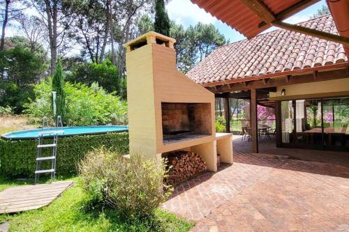 a outdoor oven with a table and a pool at Casa Acuario - großes Haus mit besonderem Flair in Punta del Este