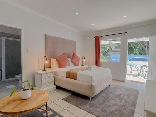 Schlafzimmer mit einem Bett, einem Tisch und einem Fenster in der Unterkunft Amoris Guesthouse - In Brooklyn in Pretoria