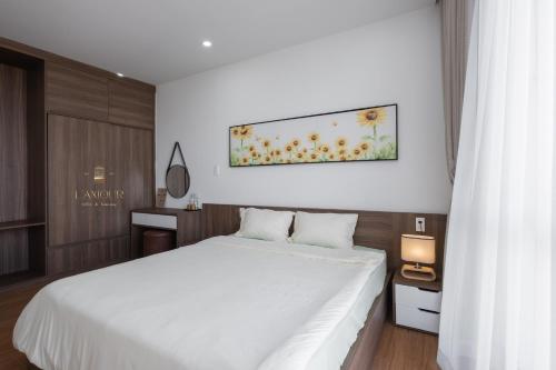 a bedroom with a white bed and a painting on the wall at Lamour homestay in Thôn Kim Long (1)