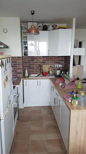 une cuisine avec des armoires blanches et un sol carrelé dans l'établissement Appartement spacieux aux portes de Paris, à Bagnolet